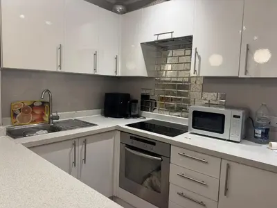 a kitchen with white cabinets and a stove top oven at Amazing Flat in London in Moffat