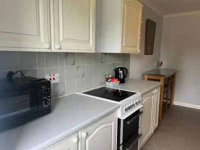 a kitchen with white cabinets and a black stove top oven at Stay Still Indian Court in Dalston