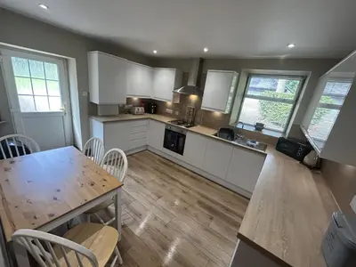 a kitchen with white cabinets and a wooden table at The Stables in Symington in Symington