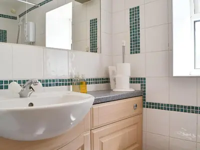 a white bathroom with a sink and a mirror at Brigham Farm Apartments in Keswick