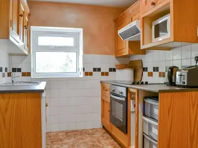 a small kitchen with wooden cabinets and a window at Brigham Farm Apartments in Keswick