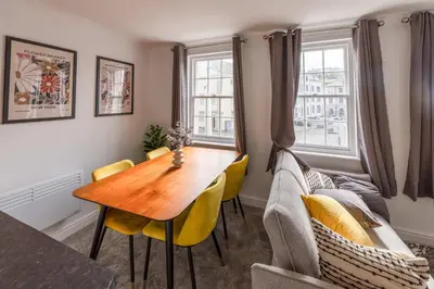 a dining room with a wooden table and yellow chairs at Bright 1 Bed Harbour-side Apartment with Sea Views in Whitehaven