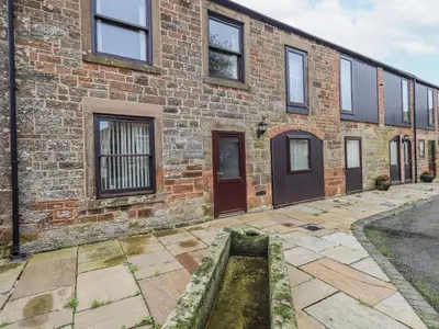 a brick building with a water fountain in front of it at The Coach House in Wigton
