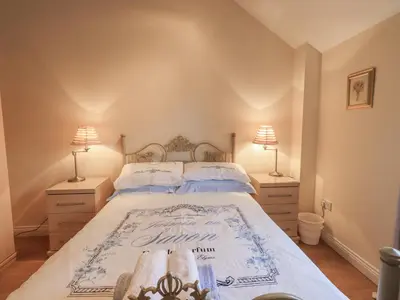a bedroom with a large bed with two lamps at Millers Cottage in Wigton