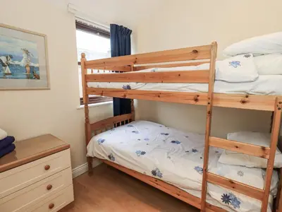 a bedroom with two bunk beds and a dresser at Millers Cottage in Wigton