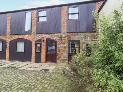a brick house with a door and a yard at Millers Cottage in Wigton