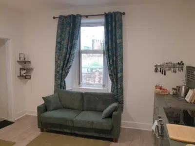 a living room with a green couch and a window at Modern Two-Bedroom Apartment Near River with Free Parking & WiFi in Dumfries