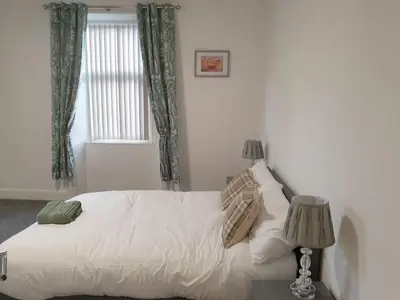 a bedroom with a white bed with two lamps and a window at Modern Two-Bedroom Apartment Near River with Free Parking & WiFi in Dumfries