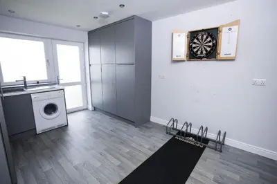 a room with a washing machine and a dartboard on the wall at Fellside Hideaway in Keswick
