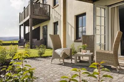 a patio with wicker chairs and a table at The Hide - Ridgestone in Penrith
