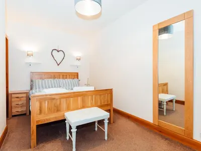 a bedroom with a bed and a mirror at Middle Byre in Girthon