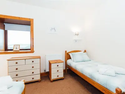 a bedroom with two beds and a dresser and a mirror at Middle Byre in Girthon