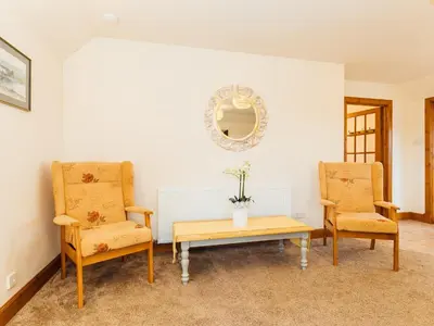 a room with two chairs and a table and a mirror at Middle Byre in Girthon