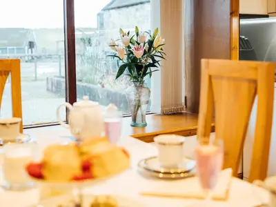a table with a vase of flowers and a vase of roses at Middle Byre in Girthon