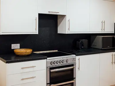 a kitchen with white cabinets and a stove top oven at The Barn in Girthon