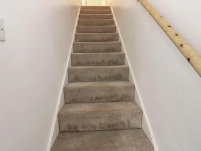 a staircase in a house with white walls and carpet at Lonsdale Street in Workington
