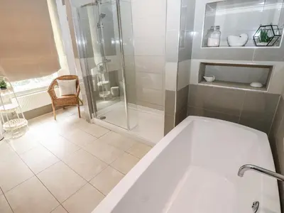 a bathroom with a shower and a bath tub at Hampton House in St Bees