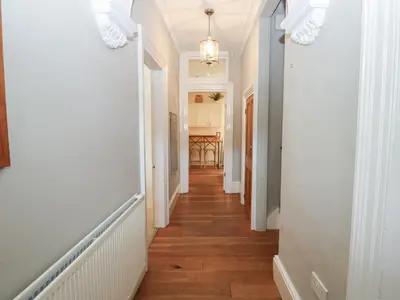 a hallway of a home with white walls and wood floors at Hampton House in St Bees