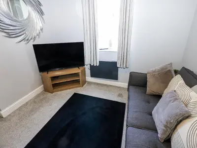 a living room with a couch and a flat screen tv at Lowther House in Whitehaven