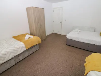 a bedroom with two beds and a closet at Curwen Apartment in Workington