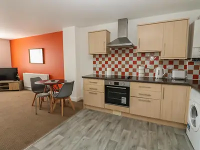 a kitchen with wooden cabinets and a table and chairs at Curwen Apartment in Workington