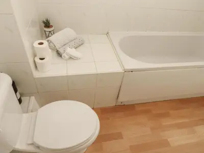 a white bathroom with a toilet and a tub at Curwen Apartment in Workington