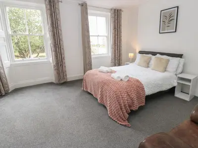 a bedroom with a bed with a blanket and two windows at Georgian Town House in Whitehaven
