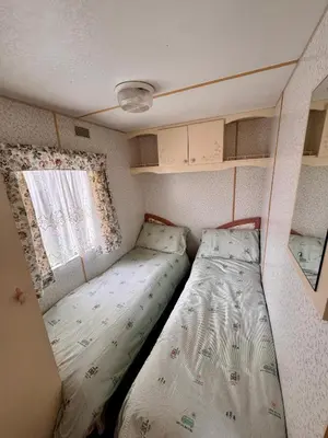 a small bedroom with two beds and a window at No 26 Mountain View in Cockermouth