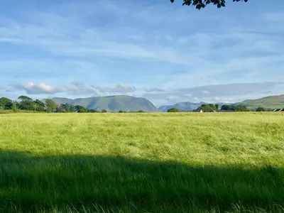 a field of green grass with mountains in the background at No 26 Mountain View in Cockermouth