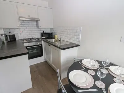 a kitchen with a table with plates and wine glasses at Kirkgate Cottage in Cockermouth