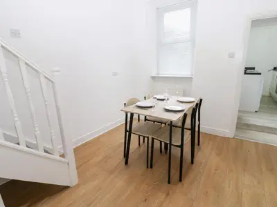 a dining room with a table and chairs and stairs at Holly House in Whitehaven