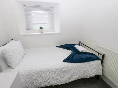 a bedroom with a bed with a blue blanket on it at Holly House in Whitehaven