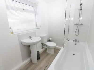 a white bathroom with a toilet and a sink at Holly House in Whitehaven