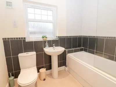 a bathroom with a toilet and a sink and a bath tub at Lingla House in Frizington