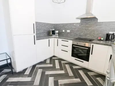 a kitchen with white cabinets and a geometric floor at Lowther Apartment in Whitehaven
