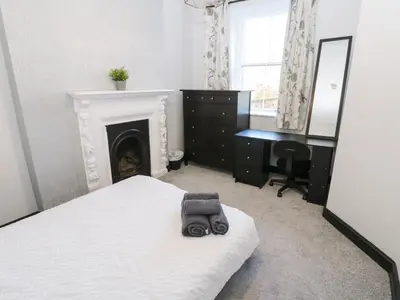 a bedroom with a bed with a fireplace and a desk at Lowther Apartment in Whitehaven