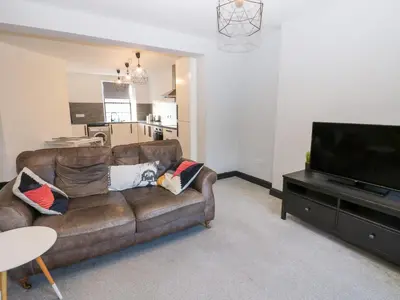 a living room with a brown couch and a flat screen tv at Lowther Penthouse in Whitehaven