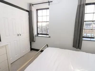 a bedroom with a bed and two windows at Lowther Penthouse in Whitehaven