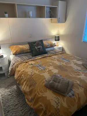 a bedroom with a large bed with a brown comforter at 108 Lochview in Newton Stewart