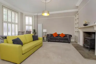 a living room with a yellow couch and a fireplace at 2 On The Green in Moffat