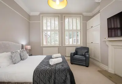 a bedroom with a bed and a black chair at 2 On The Green in Moffat