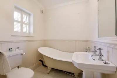 a bathroom with a tub and a sink and a toilet at 2 On The Green in Moffat