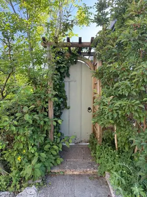 an entrance to a garden with a white door at Cosy Cottage in Cotswolds in Moffat