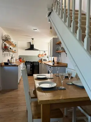 a kitchen and dining room with a wooden table and stairs at Cosy Cottage in Cotswolds in Moffat