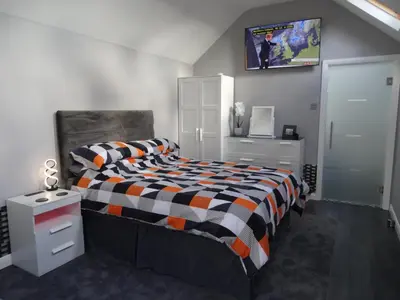 a bedroom with a bed and a tv on the wall at Lazy Lodge in Foxdale