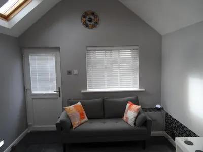 a living room with a couch and a clock on the wall at Lazy Lodge in Foxdale