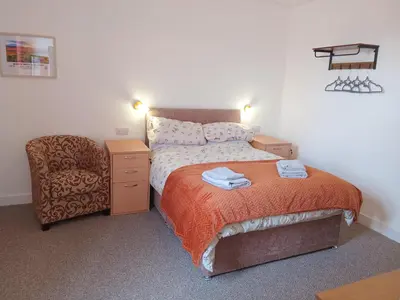 a small bedroom with a bed and a chair at Double Ensuite - City centre homestay - Peterill Room - in Carlisle
