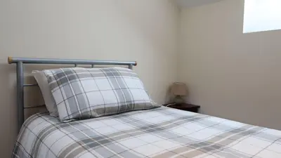 a bed with a plaid pillow on top of it at Wee Newton in Twynholm