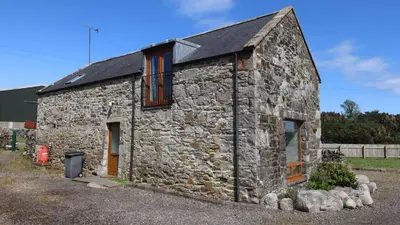 an old stone building with two windows on it at Wee Newton in Twynholm