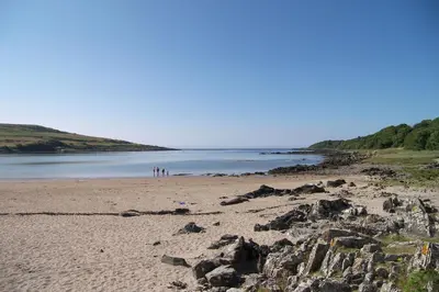 a group of people standing on a beach near the water at Wee Newton in Twynholm